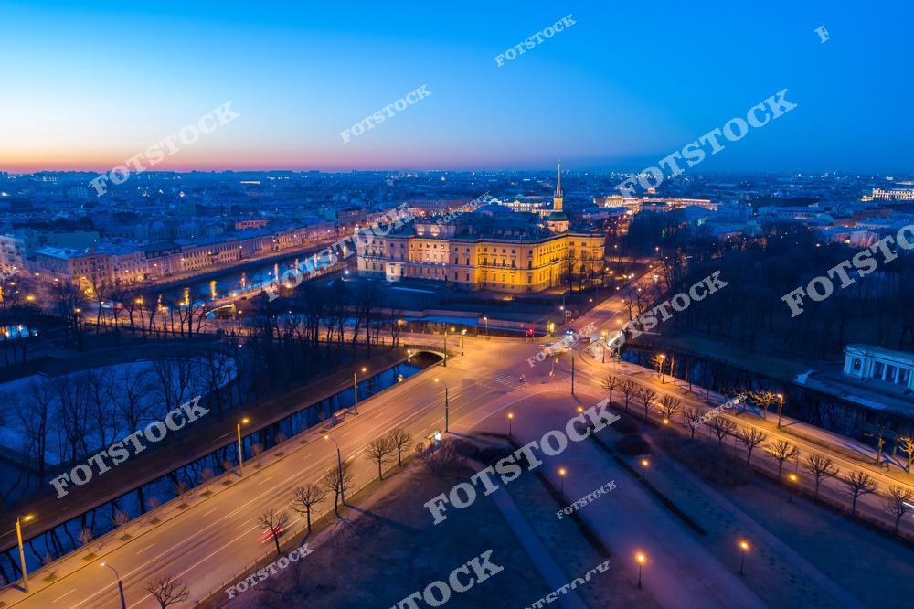 Фотография ночного Санкт-Петербург, Россия. На изображении запечатлён Михайловский замок, освещённый вечерней подсветкой. Фотоснимок передаёт атмосферу ночного Петербурга: мягкий свет фонарей, отражения на воде и выразительные формы исторической архитектуры. Фото подчёркивает значимость экскурсионных маршрутов по Михайловскому замку и представляет Санкт-Петербург как важный культурный центр для путешествий по Российской Федерации. Иллюстрация отражает традиции русской архитектуры и туристическую привлекательность города.